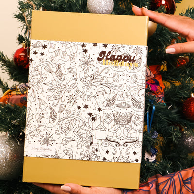 Person holding a gift box with 'Happy' text against a Christmas tree background