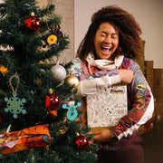 Person standing next to a decorated Christmas tree indoors
