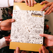 Chocolate Makers holding an advent calendar book with Christmas-themed illustrations in front of a decorated Christmas tree to be delivered in Toronto, Canada
