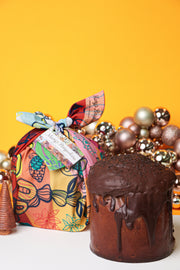 Chocolate cake with a colorful gift bag and decorative items on a yellow background